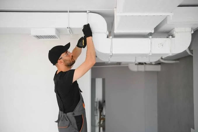 HVAC technician checking overhead air duct connections