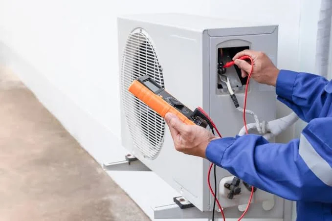 Technician testing an outdoor air conditioner with a handheld electrical meter