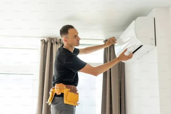Installer fitting a wall-mounted air conditioning unit in a home