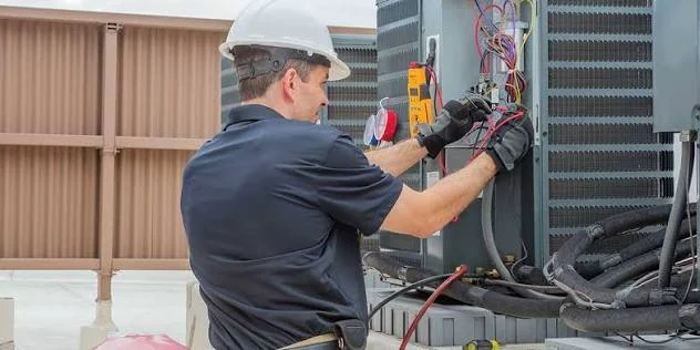 Technician inspecting electrical connections on an outdoor HVAC system